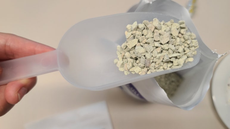 Realistic photo of a beginner scooping natural zeolite granules into a small transparent water tank,