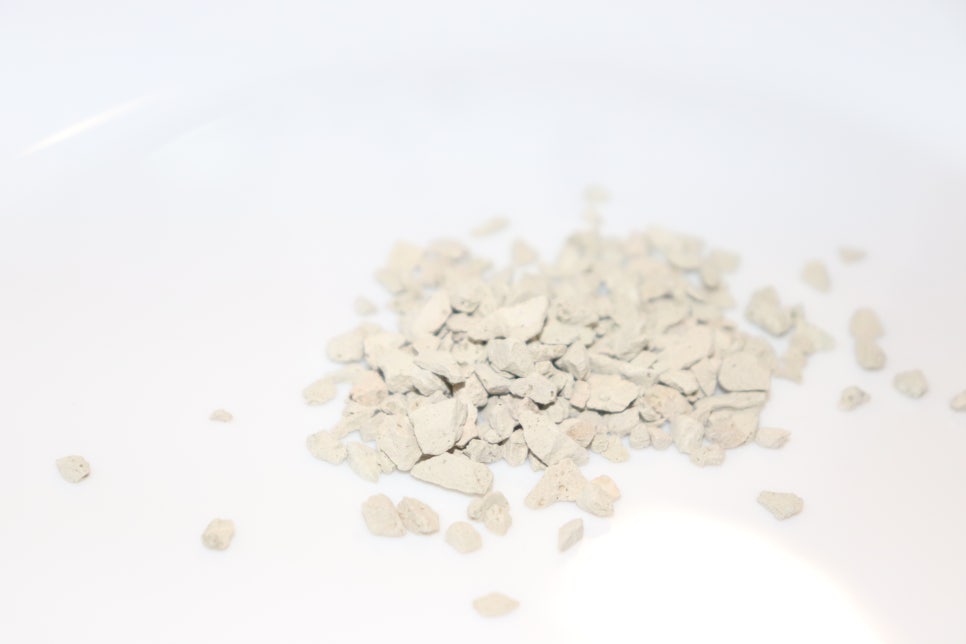 Close-up of white natural zeolite crystals on a clean lab bench with glassware and a subtle, blurred