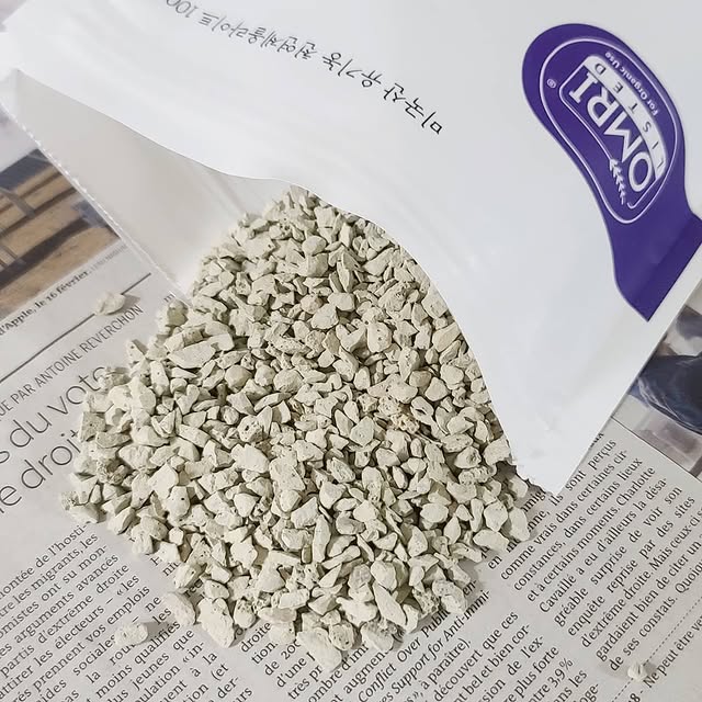 Realistic photo of farmland with light-colored zeolite granules being spread on soil in the morning 