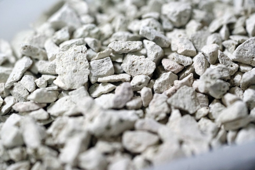 Macro shot of porous white zeolite crystals illuminated by cool lab lighting, emphasising intricate 