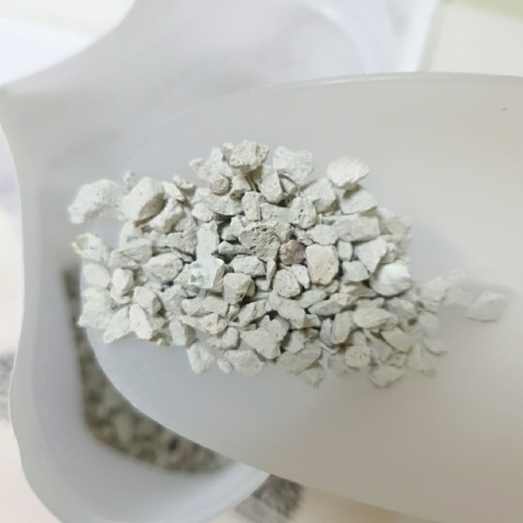 Close-up in a clean lab showing two unlabeled glass jars containing different white zeolite powders,