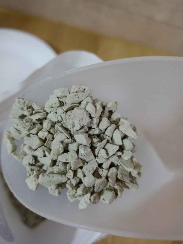 Macro shot of two types of zeolite media in small bowls: irregular natural granules and uniform synt