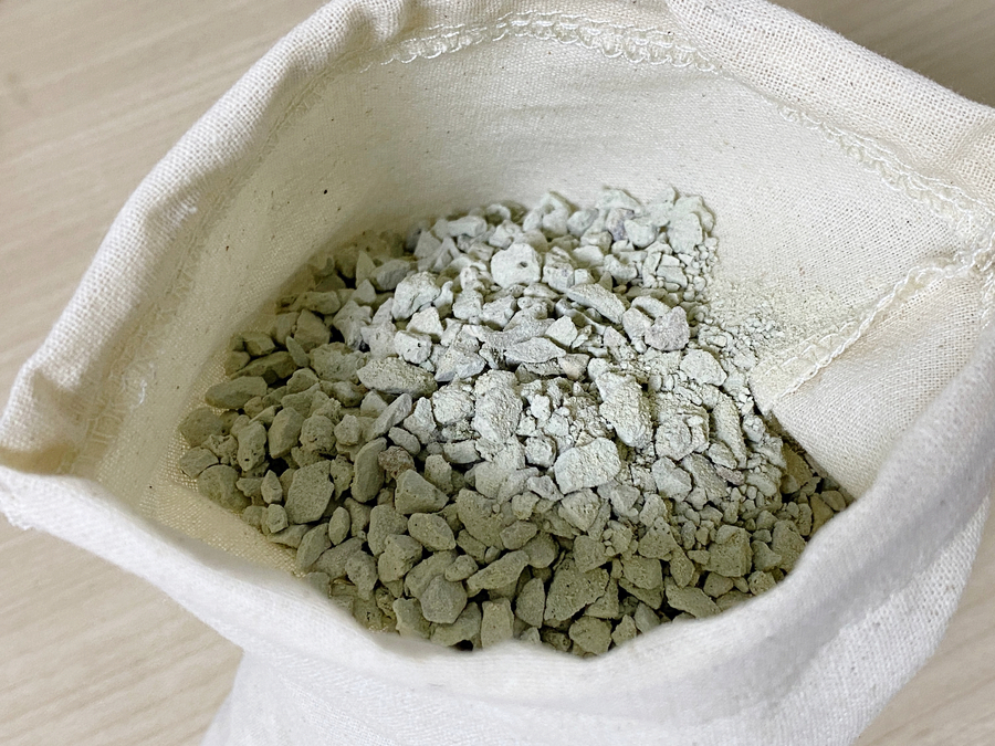 Close-up of fabric fibers coated with fine zeolite particles, showing embedded beads and a micro-por