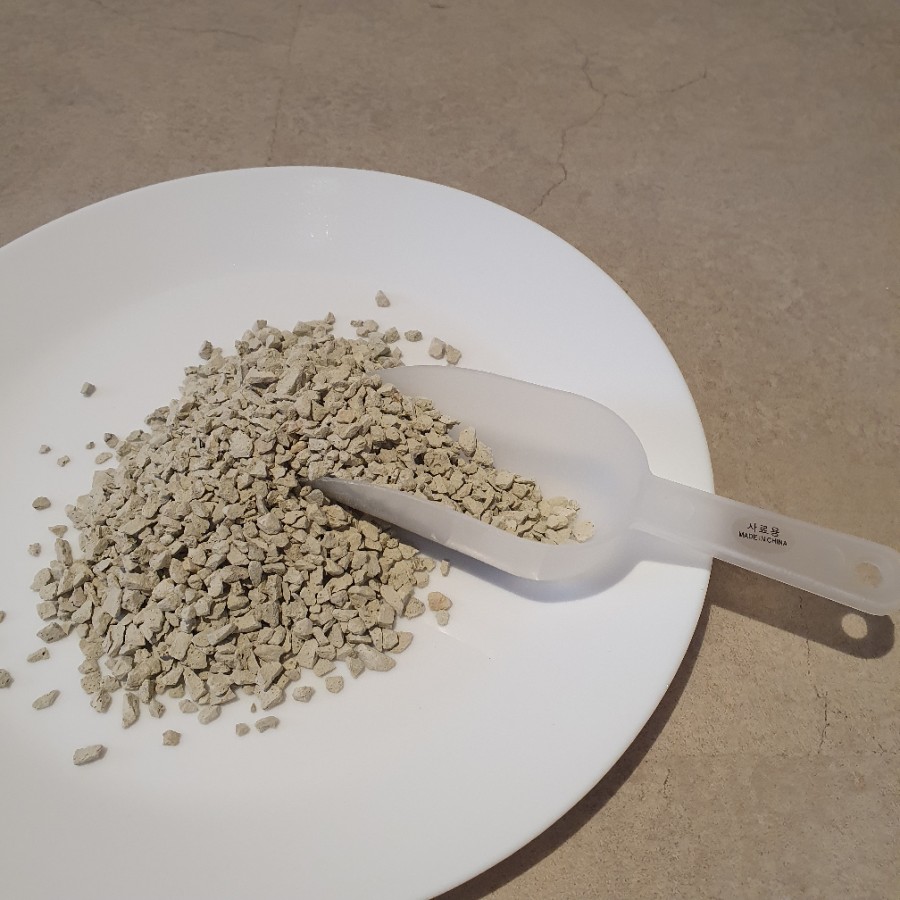 Kitchen sink area with baking soda being poured from a measuring spoon into a drain, clean counterto
