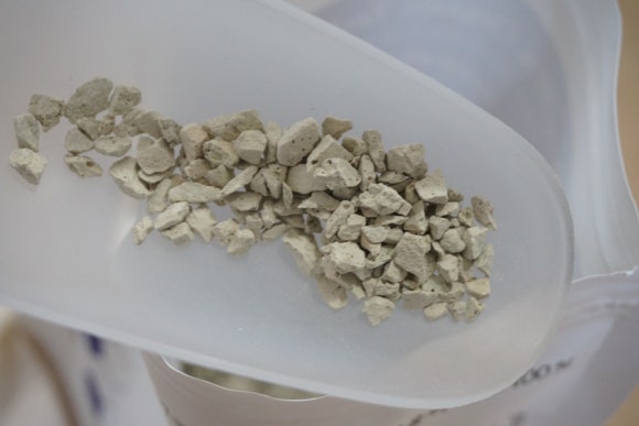 Construction site scene showing concrete elements and a container with zeolite additive being prepar