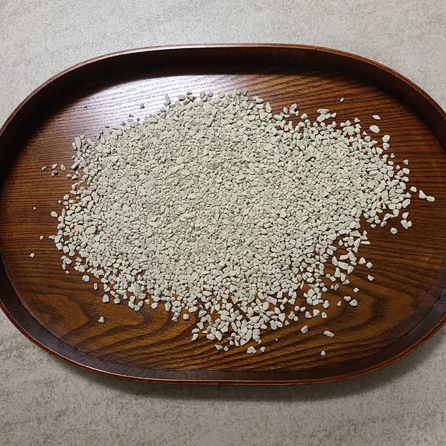 Close-up of white zeolite pellets on a stainless steel conveyor belt inside a production line, dust-