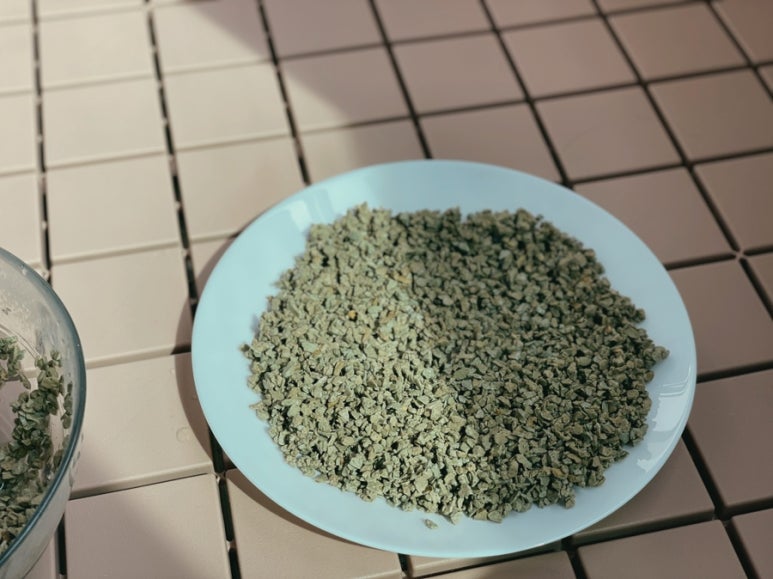 Outdoor sunny balcony with a tray of zeolite placed in direct sunlight on light tiles, emphasizing s