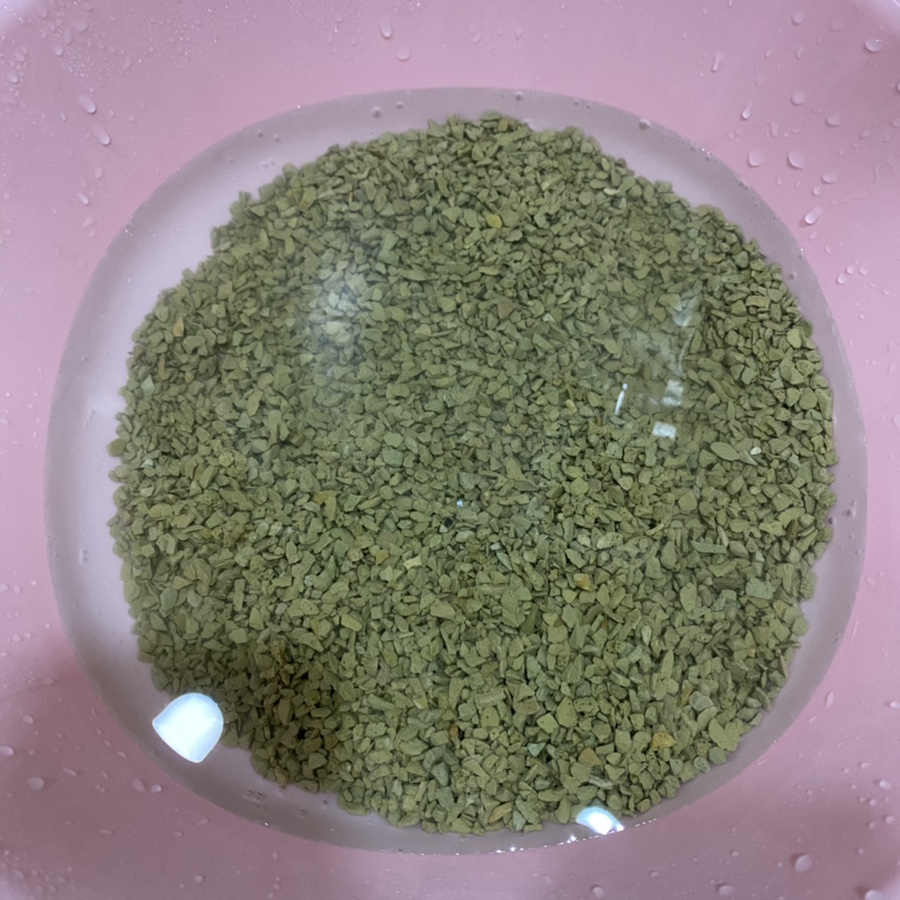 Close-up macro of zeolite pellets: granular purple-blue beads submerged in water, high detail textur