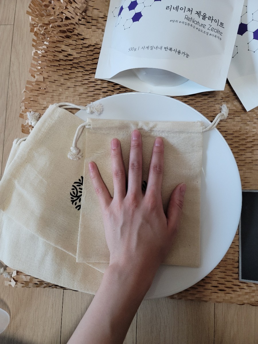 Sunlit window sill with hands placing a zeolite sachet on a tray for sun drying, outdoor light, real