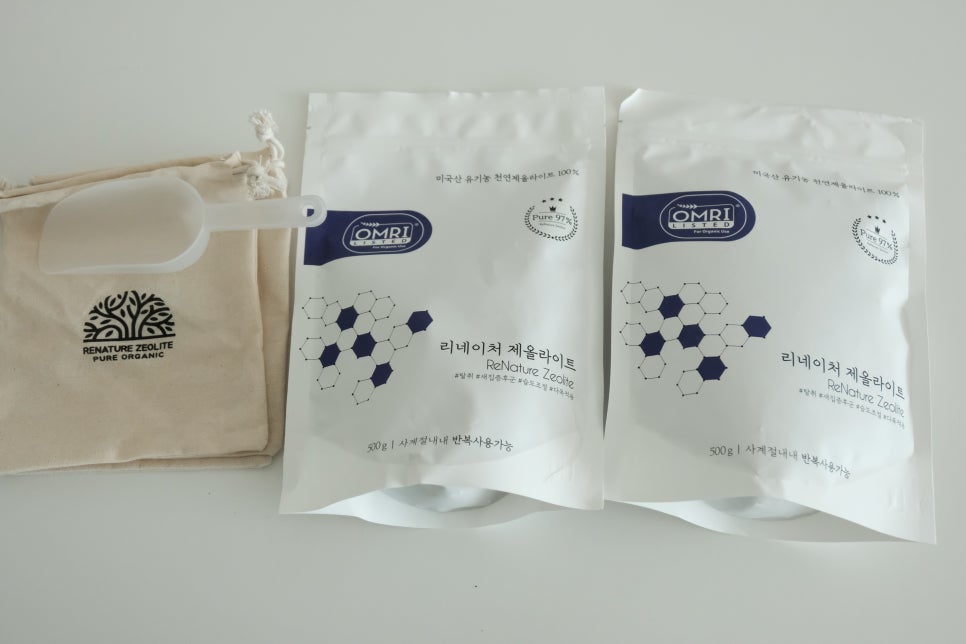 Minimalist display of two zeolite bags on a clean surface, a small scale and coins arranged nearby t