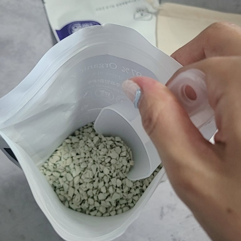 Close-up of probiotic drops being added to baby bottle or cup, caregiver hands, clean kitchen, soft 