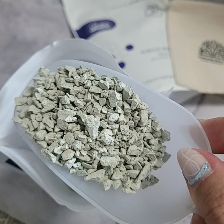 Close-up of a hand holding a natural zeolite sample with a blurred background featuring abstract saf
