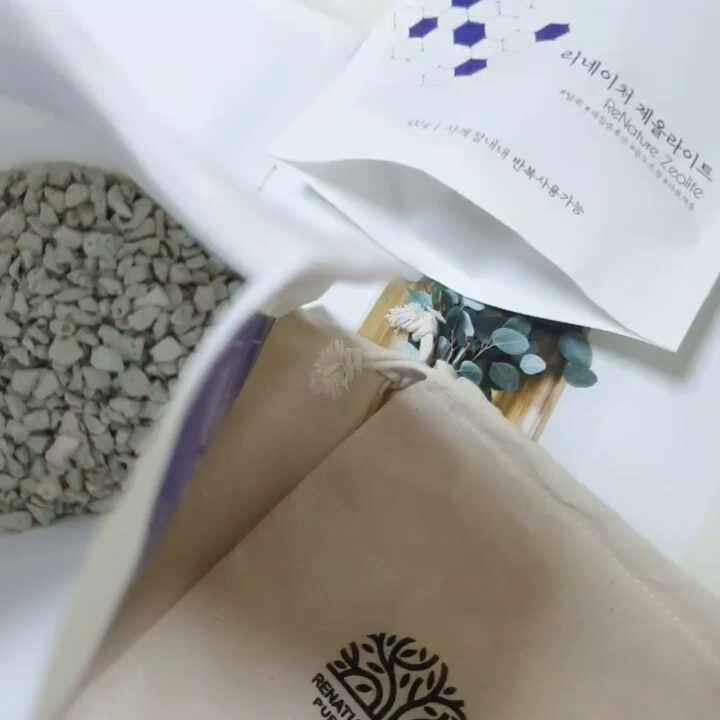 Decorative display with a small glass bottle containing essential oil droplets and a linen sachet fi