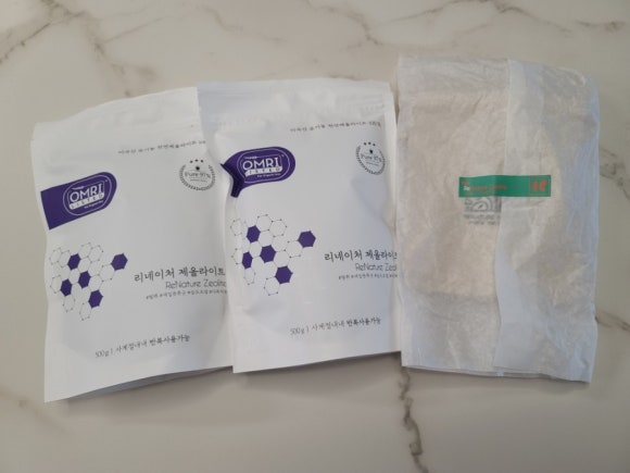 Plain, unlabeled zeolite packaging on a kitchen scale showing a large weight, with a clean lab-like 